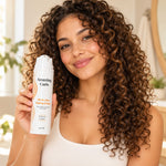 Vrouw met krullend haar houdt All-in-One Styling Cream van Amazing Curls vast