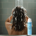 Vrouw wast krullendhaar onder douche met Amazing Curls Smart Clean Shampoo krullenproducten cgmethode