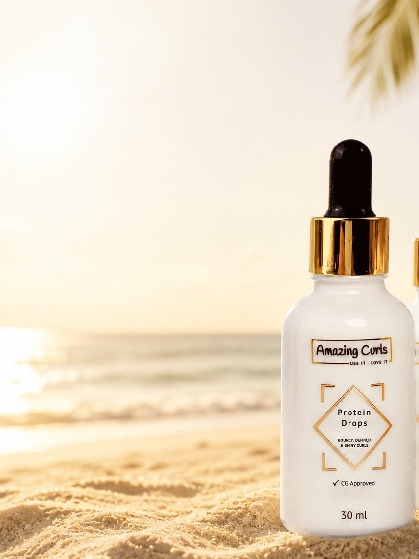 Flesje met proteïne druppels van Amazing Curls op het zand met zonlicht en zee op de achtergrond.